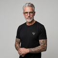 Model im schwarzen Low-key T-Shirt vor grauem Hintergrund
